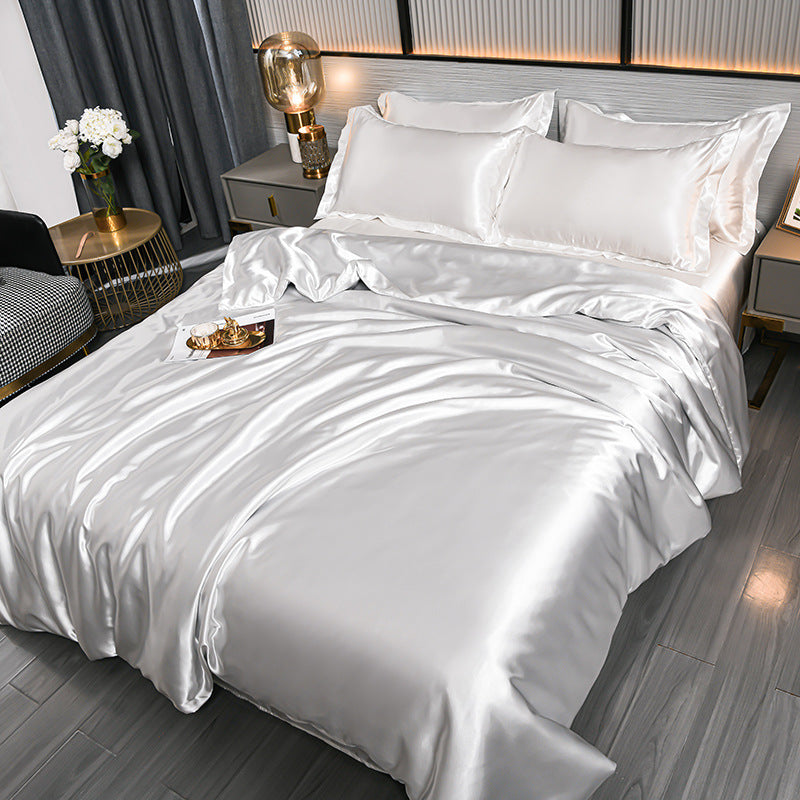White satin bedding set on a bed in a bedroom setting with decor elements.