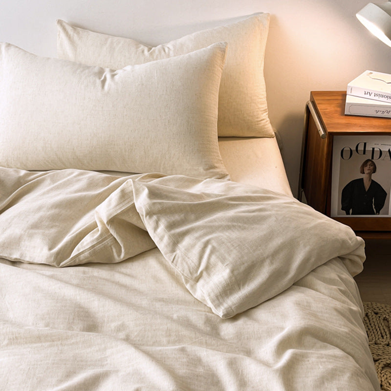 Neatly made bed with beige bedding and pillows, nightstand with lamp and photo frame.