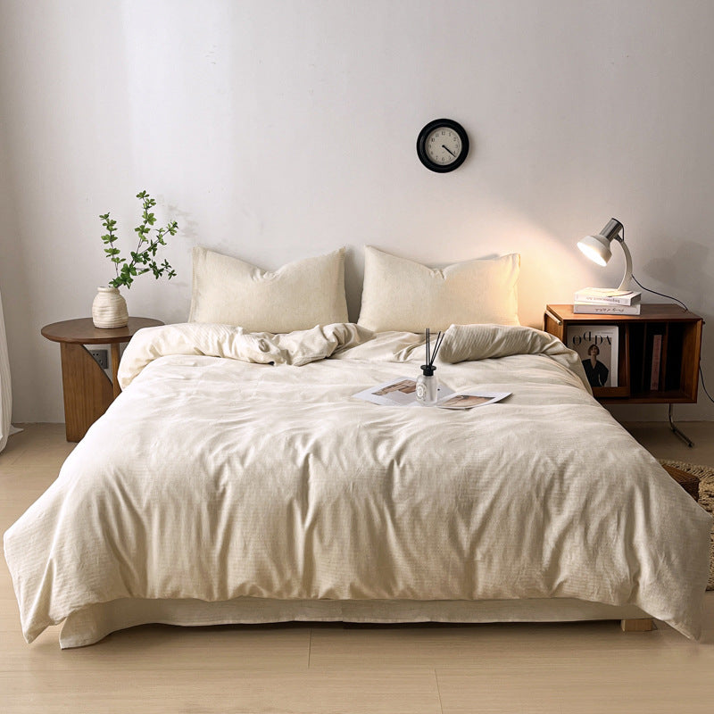 Neatly made bed with beige bedding in a minimalistic bedroom.