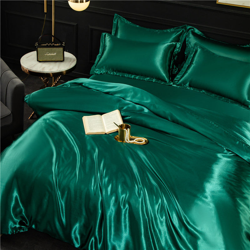 Teal satin bedding set on a bed with a side table and lamp in the background.