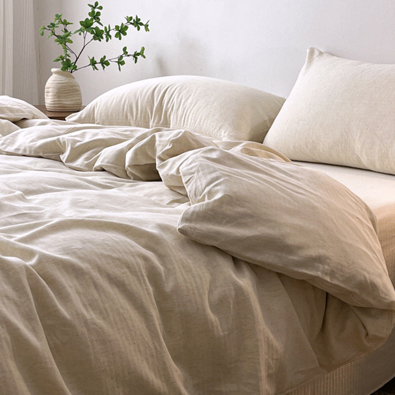 Neatly made bed with beige bedding and pillows, plant decor on nightstand.
