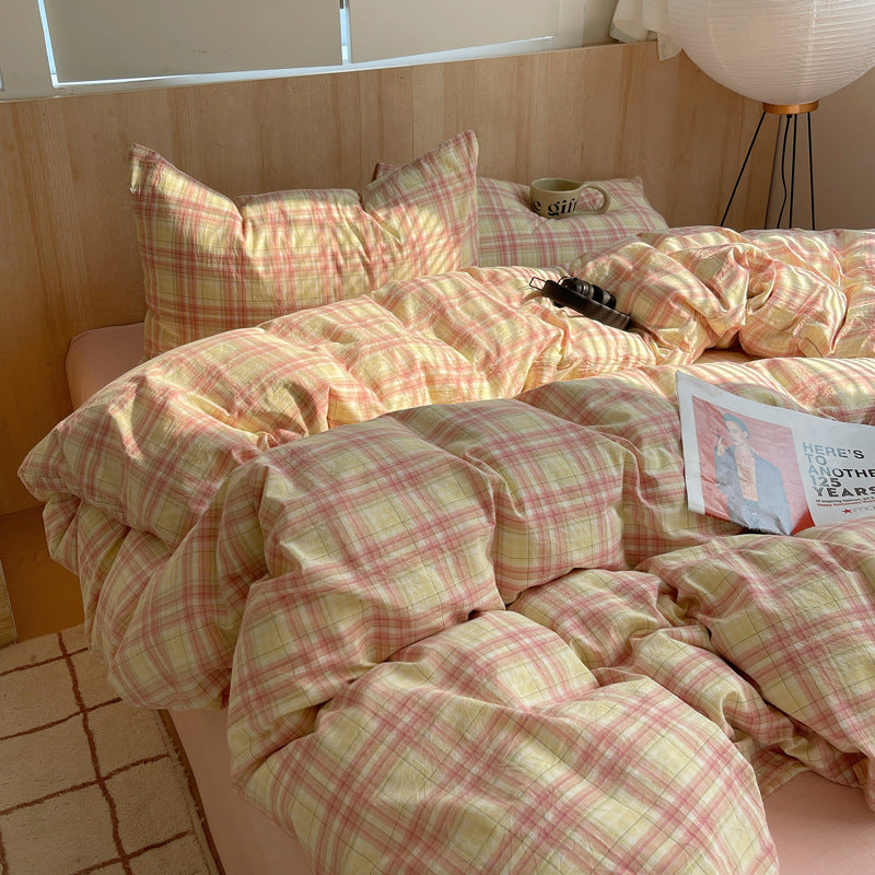 Bed with pink and green plaid bedding in a softly lit room.