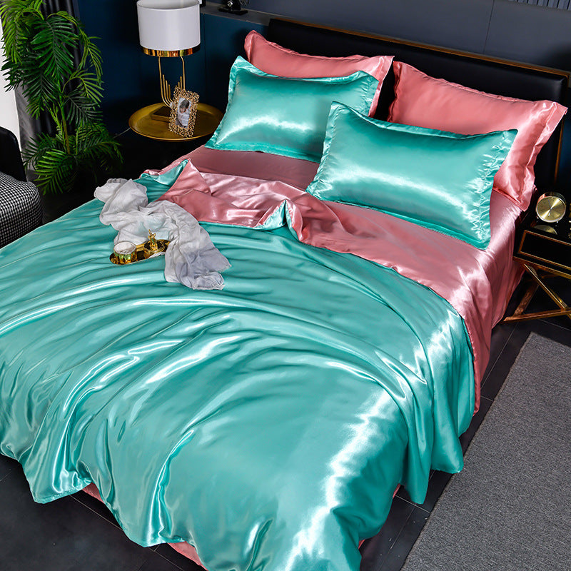 Turquoise and pink satin bedding set on a bed in a bedroom.