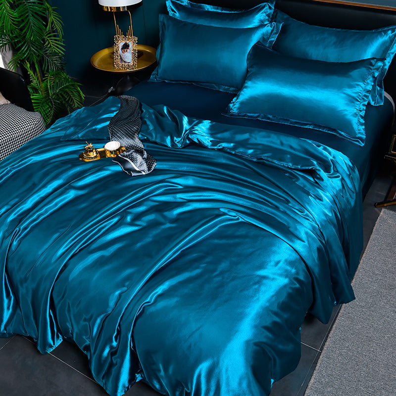 Blue satin bedding set on a bed with decorative items.