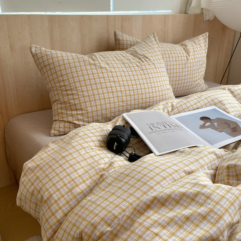 Yellow checkered bedding with a camera and magazine on a bed.