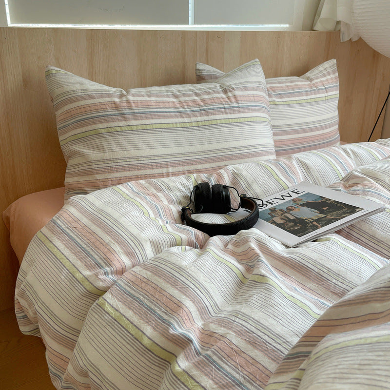 Striped bedding with a magazine and headphones on a bed in a room with wooden paneling.
