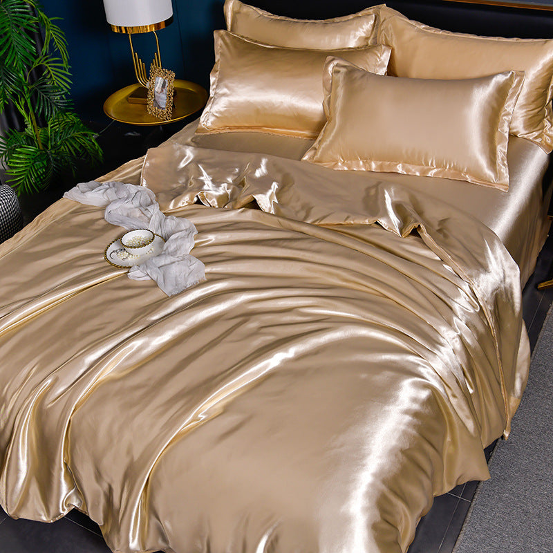 Gold satin bedding set on a bed with a nightstand and plant in the background.