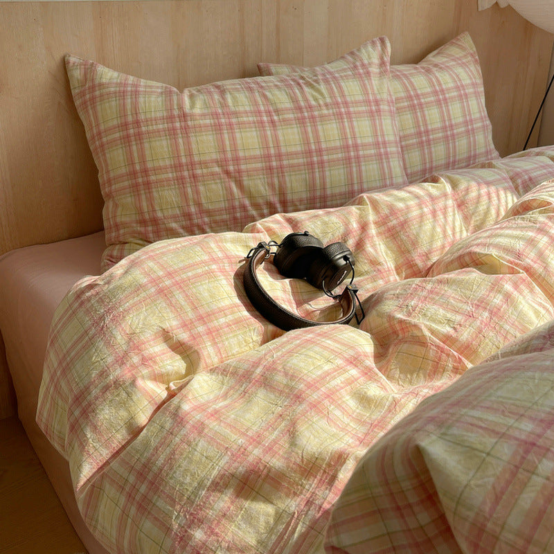 Plaid bedding with a black leather belt on a bed