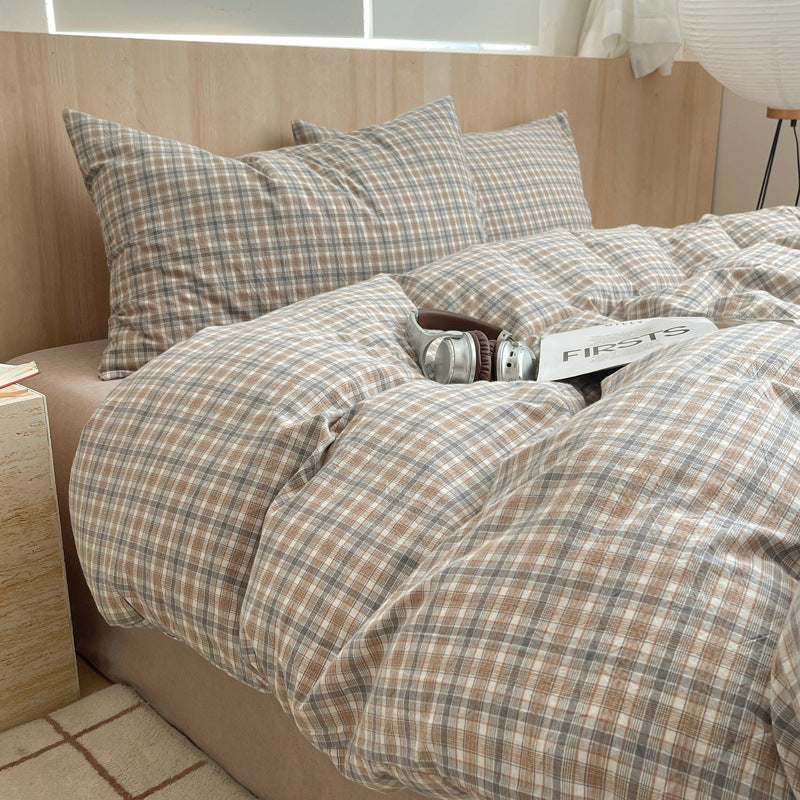 Plaid bedding set on a bed with pillows and a wooden headboard.